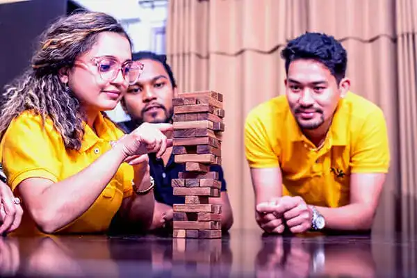 A team of three people playing tower game showcasing teamwork and trust